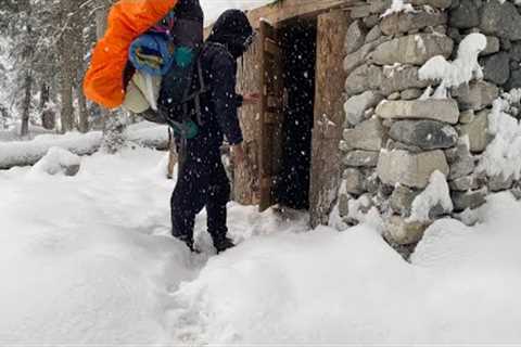 Building a stone and wood survival shelter in the woods when a snowstorm hit out of nowhere